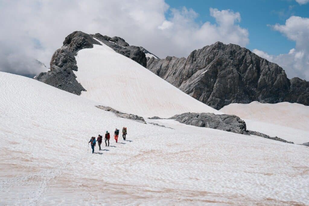 Eine Seilschaft bewegt sich über einen Gletscher, umgeben von einer beeindruckenden hochalpinen Eislandschaft. Alpinismus und Teamwork in extremen Bedingungen.